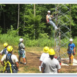 person climbing a tower with other people around him