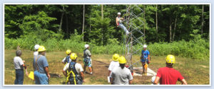 Person climbing up a tower with other people surrounding him